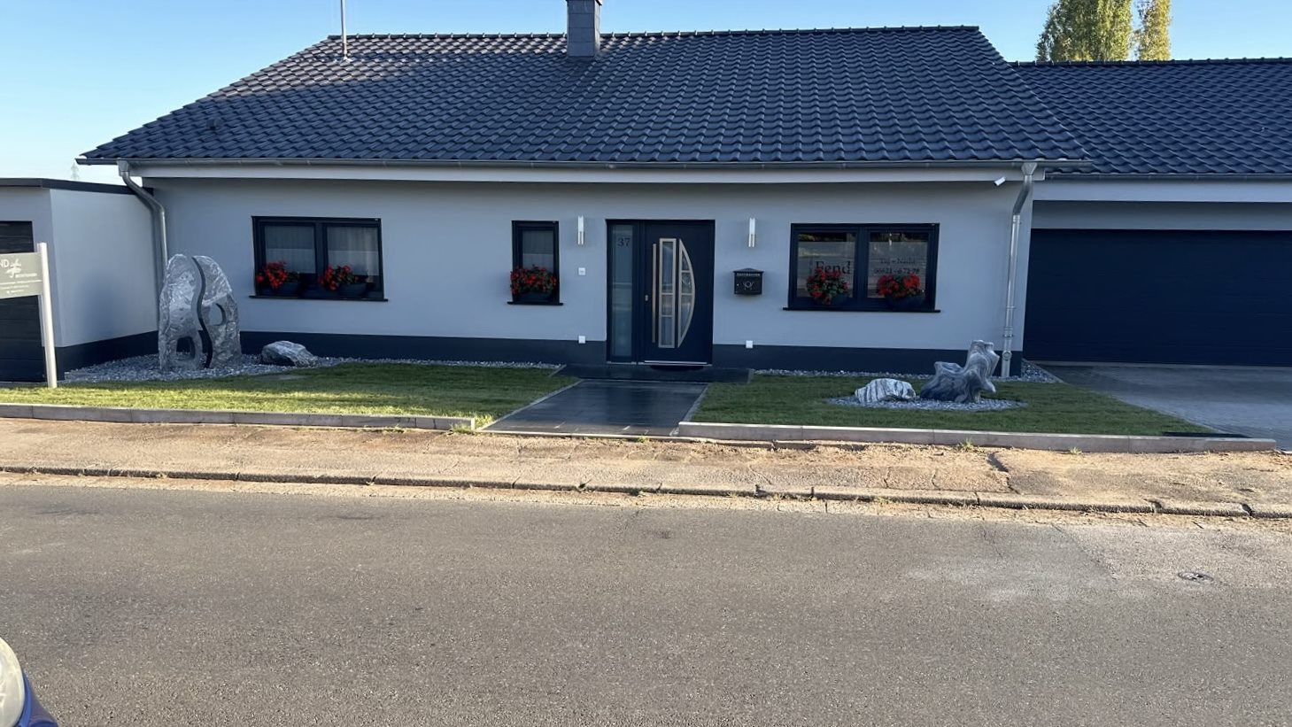 Fertiggestelltes Wohnhaus mit Vorgarten und gepflastertem Zugang.
